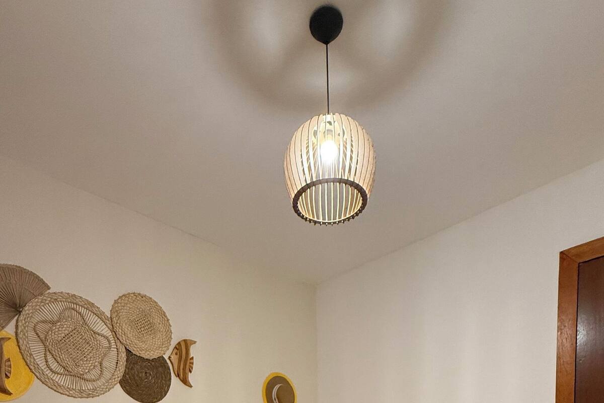 Een hotelkamer met twee bedden, een houten hoofdbord, een hanglamp en decoratieve wandkunst.