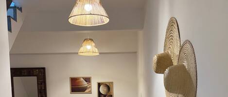Un couloir avec un banc en bois, une décoration murale en fibres tressées et un luminaire au plafond.