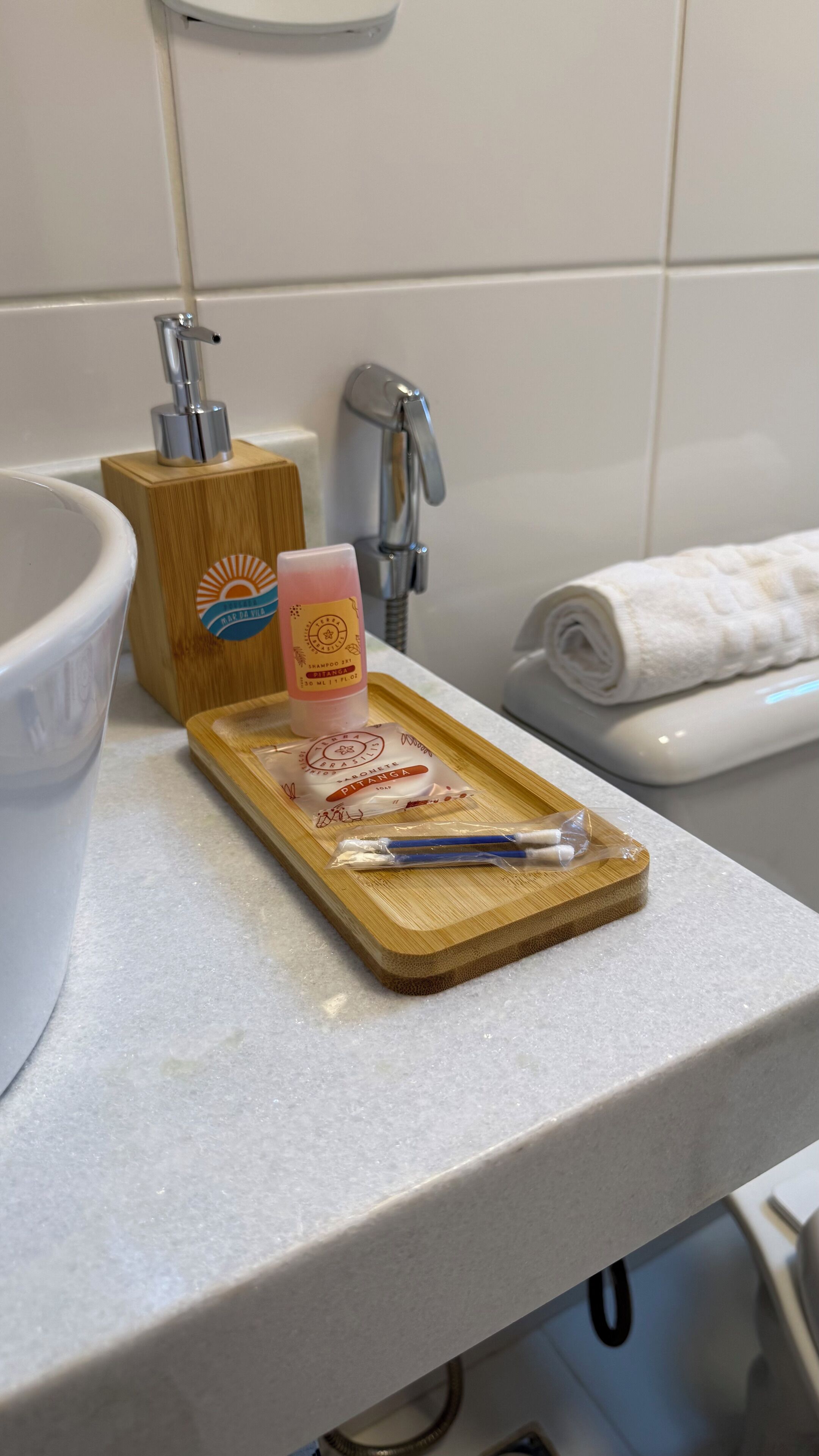 A bathroom counter with a wooden tray holding toiletries, a soap dispenser, and a toothbrush.