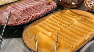 A buffet with various food items including sliced meats and pastries.