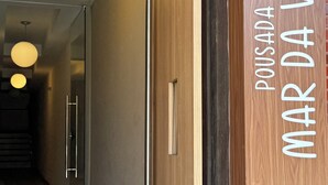 A hotel entrance with a wooden door, a sign reading "POUSADA MAR DA VILA", and a doormat. - Pousada Mar da Vila (Cabo Frio)