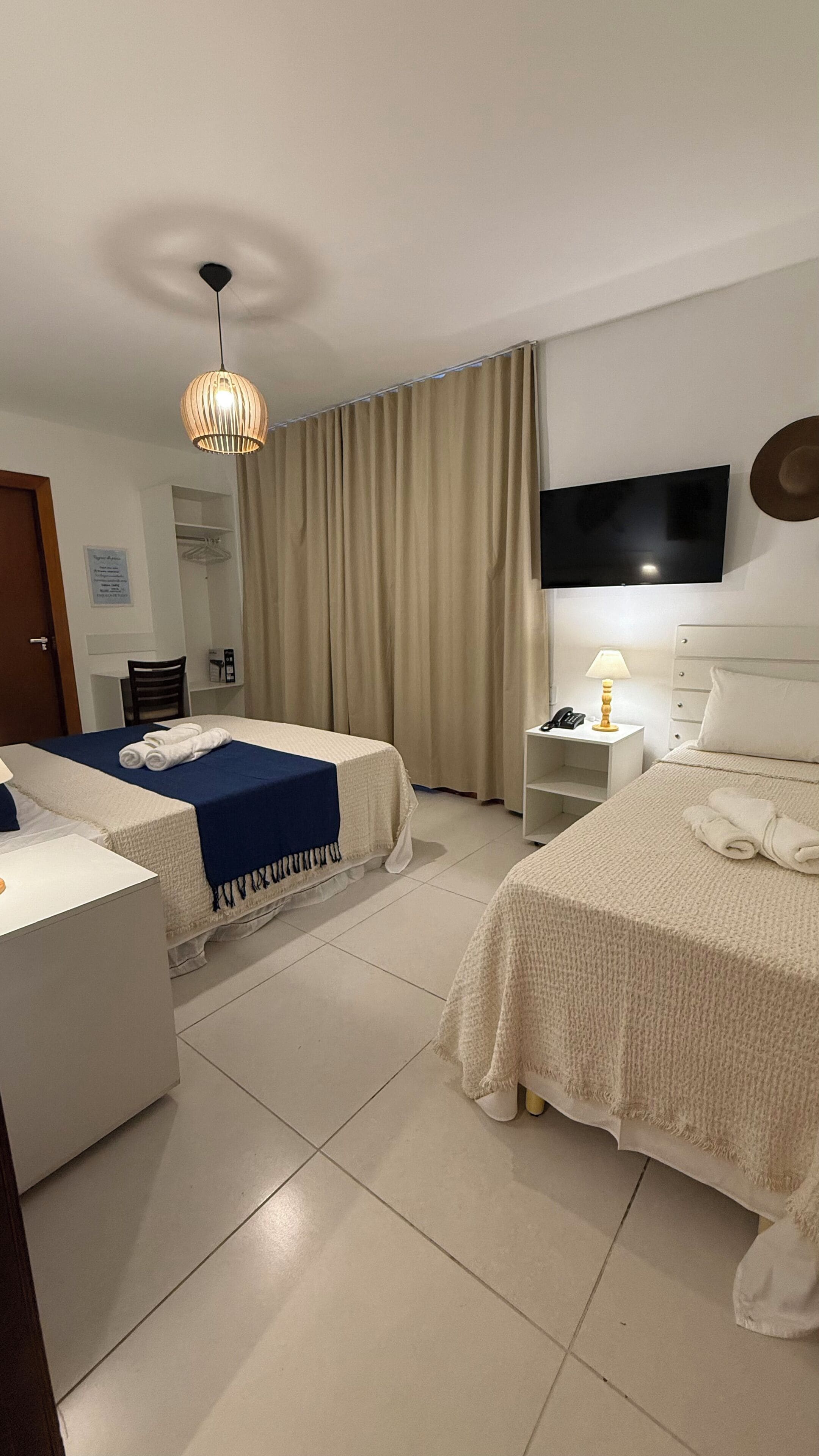 Ein Hotelzimmer mit zwei Betten, einem Fernseher, einem Schreibtisch und einem Sessel.