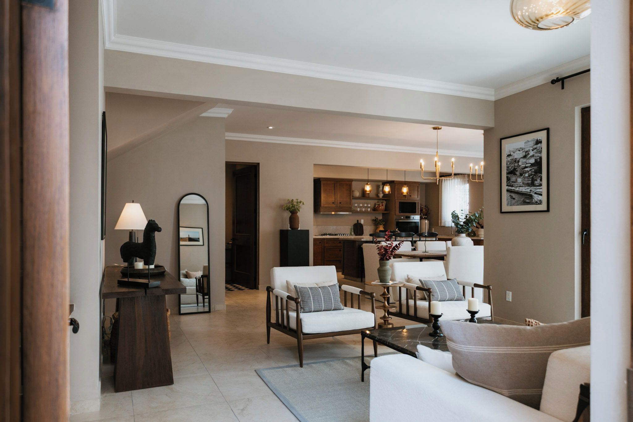 A modern living room with a dining area, kitchen, and a hallway leading to another room.