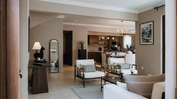 A modern living room with a dining area, kitchen, and a hallway leading to another room.