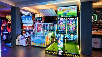 Un salón de juegos interior con diversas máquinas recreativas, incluyendo un juego de Pac-Man y una máquina de baloncesto.