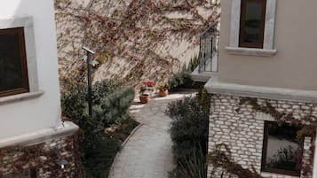 A narrow stone pathway flanked by lush greenery and flowering plants, leading to a staircase.
