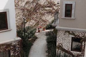 Ein schmaler, steinbelagter Weg, gesäumt von üppiger Vegetation und blühenden Pflanzen, der zu einer Treppe führt.