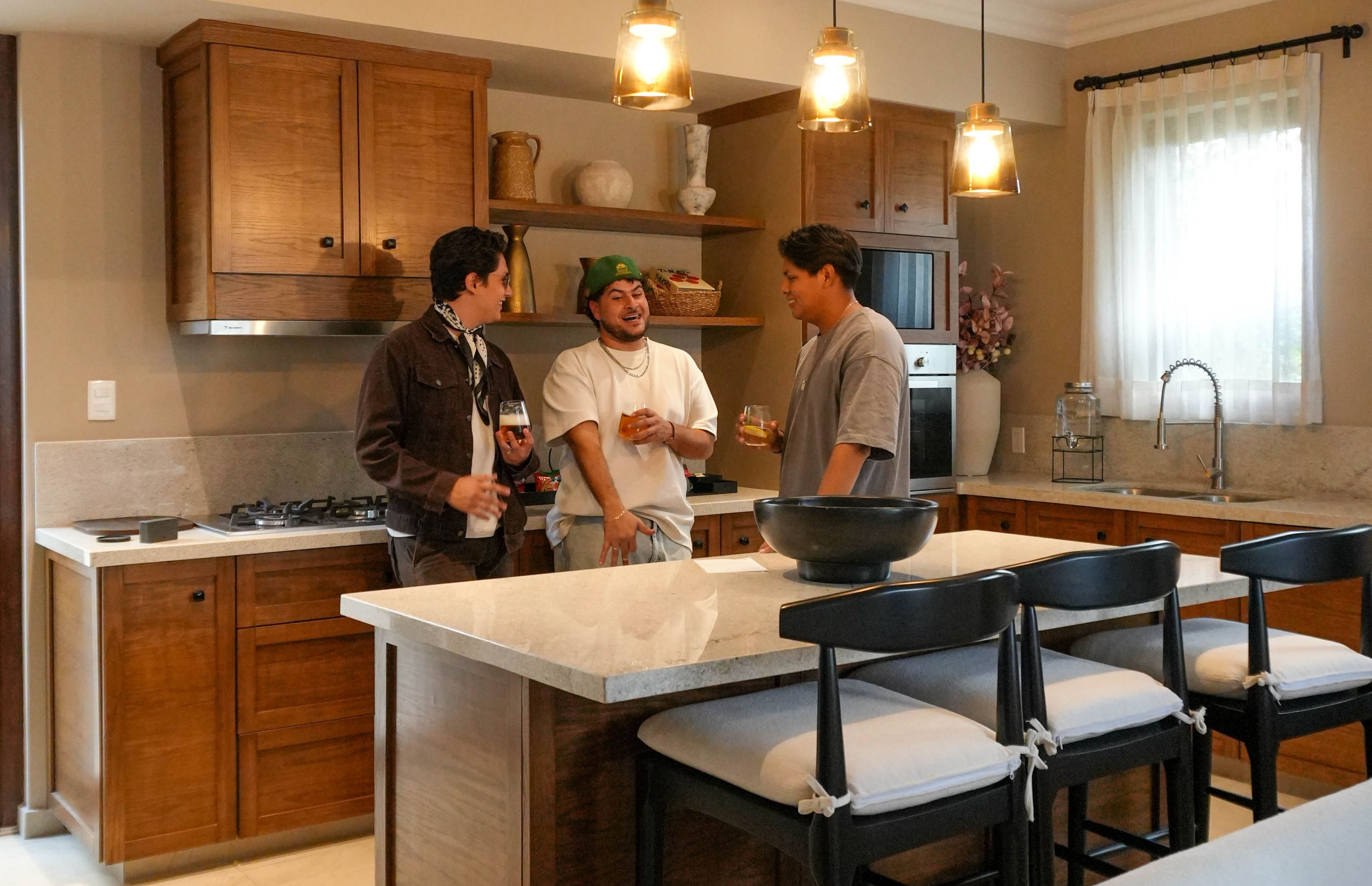 Una cocina moderna con armarios de madera, una isla central con asientos e iluminación colgante.