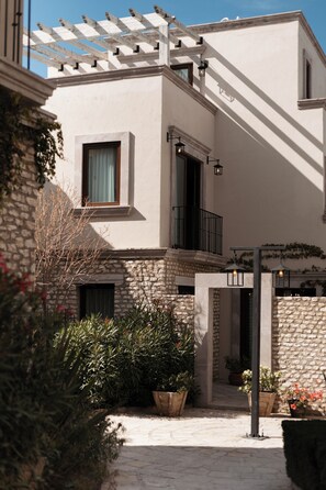 Un bâtiment doté d’une façade en pierre, d’un balcon avec une rambarde noire et d’une pergola illuminée.
