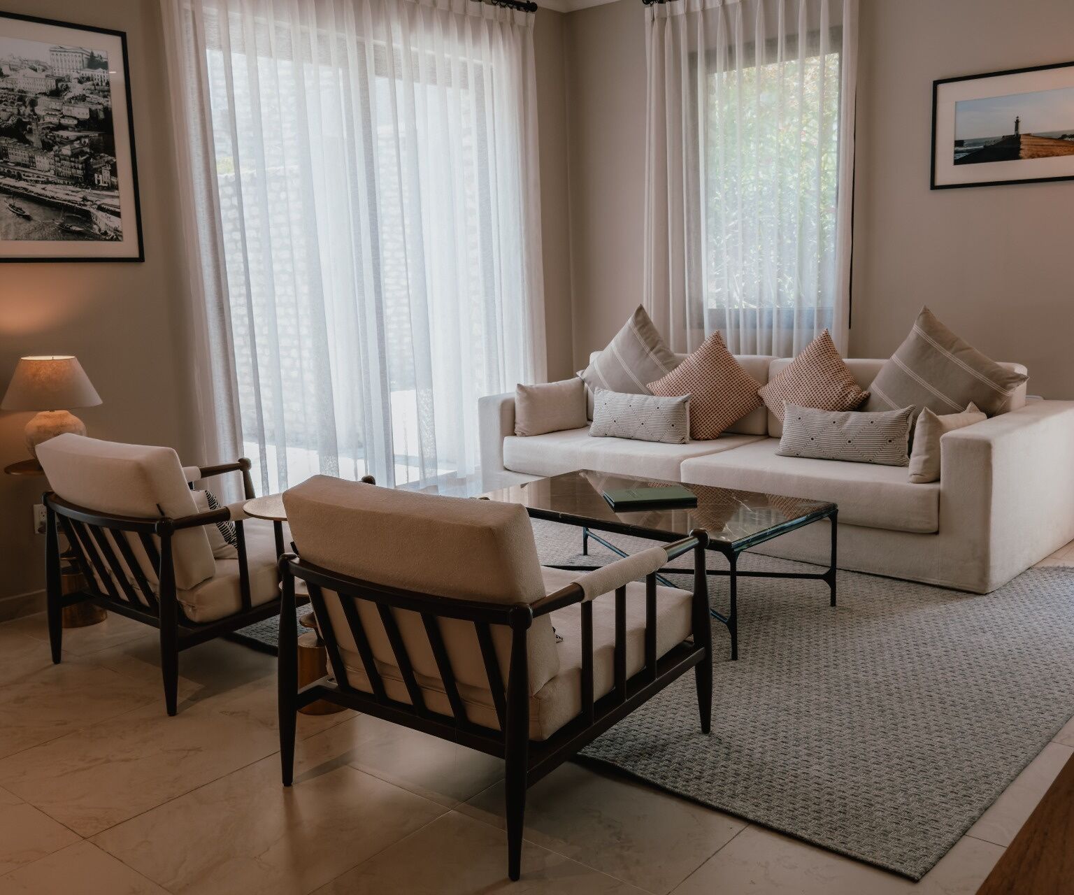 A living room with a white sofa, two armchairs, a coffee table, and a rug.