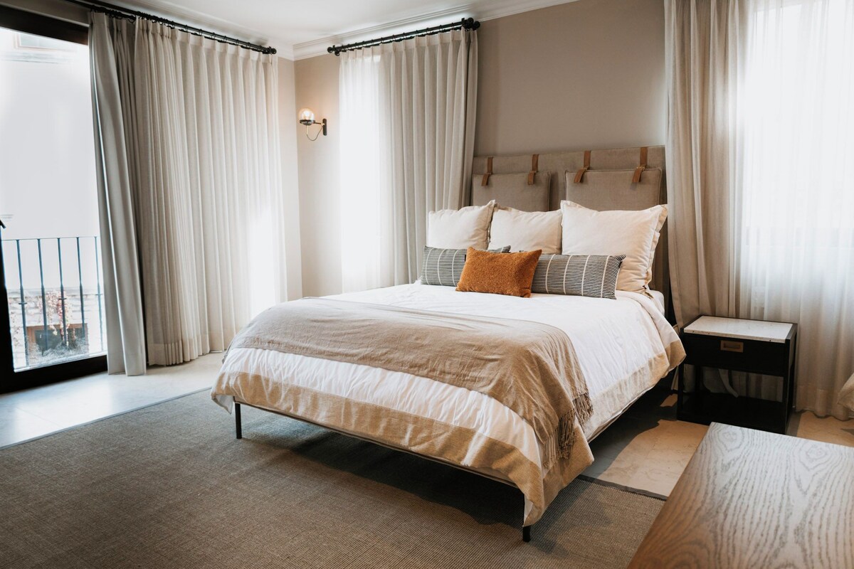 Ein modernes Hotelzimmer mit einem großen Bett, einem Nachttisch und Blick auf die Stadt.