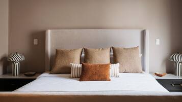 A bed with a headboard, multiple pillows, and two bedside tables with lamps.