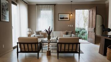Una sala de estar con un sofá, dos sillones, una mesa de centro y un florero con flores.