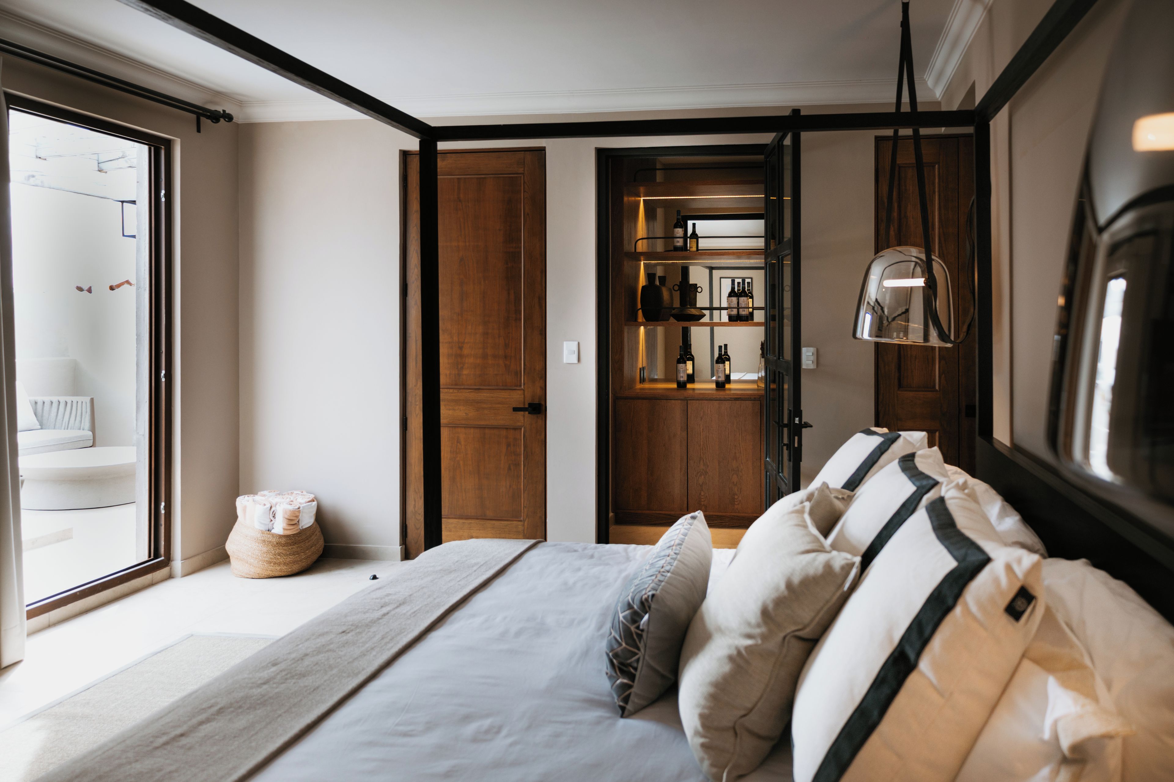 Un dormitorio con cama, almohadas, mesita de noche, lámpara y armario.