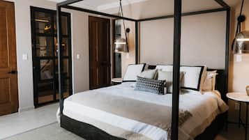 A four-poster bed with a neutral color scheme, a small round table, and a hanging light fixture.