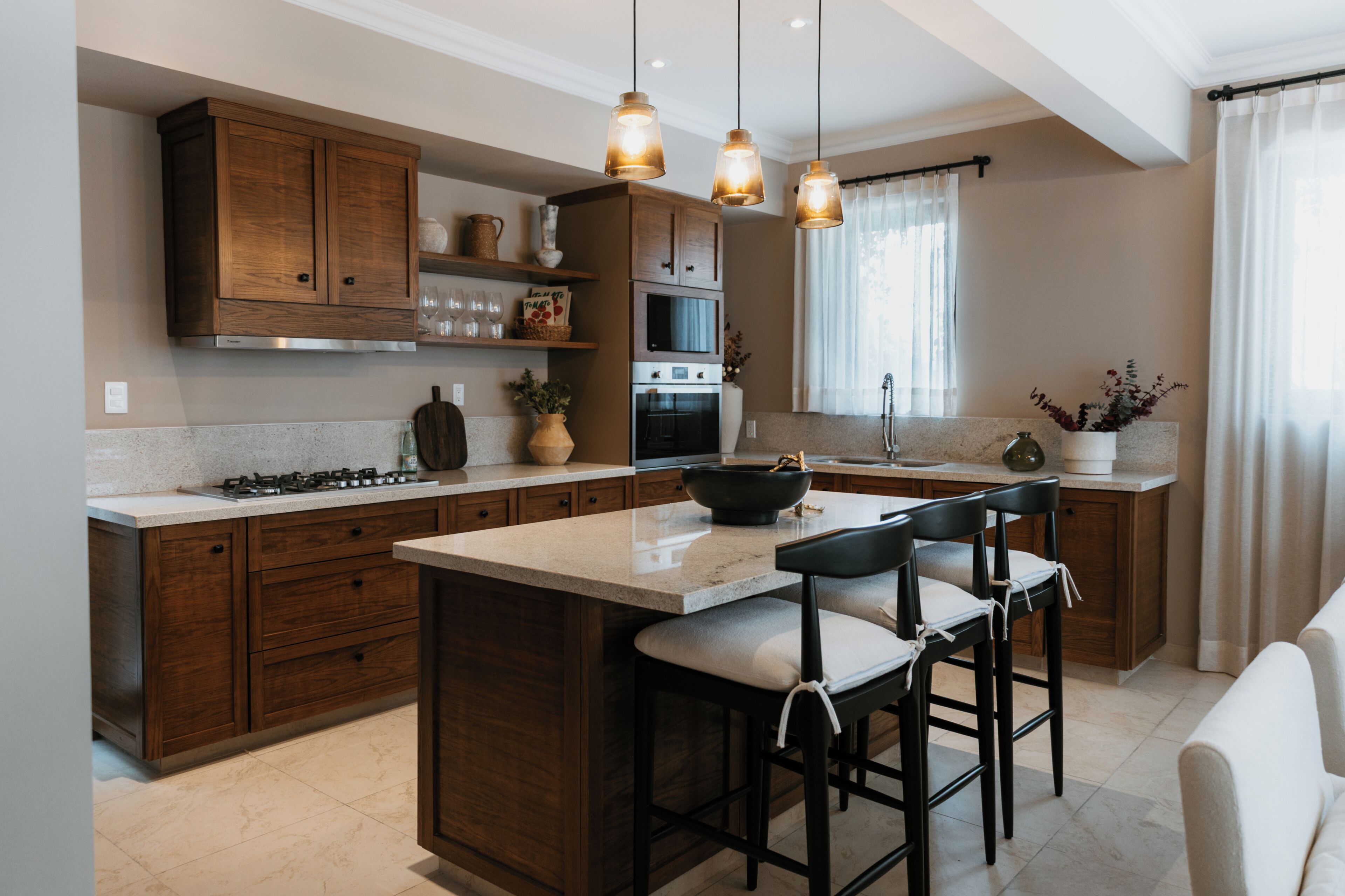 A modern kitchen with wooden cabinets, a central island with bar stools, and pendant lighting.