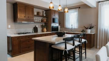 A modern kitchen with wooden cabinets, a central island with bar stools, and pendant lighting.
