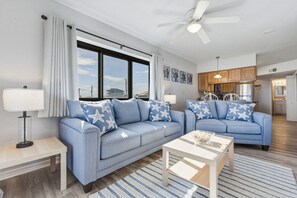 A modern living room with a sofa, coffee table, and a ceiling fan. - Condo with a beautiful view of the ocean and white sands (Navarre)