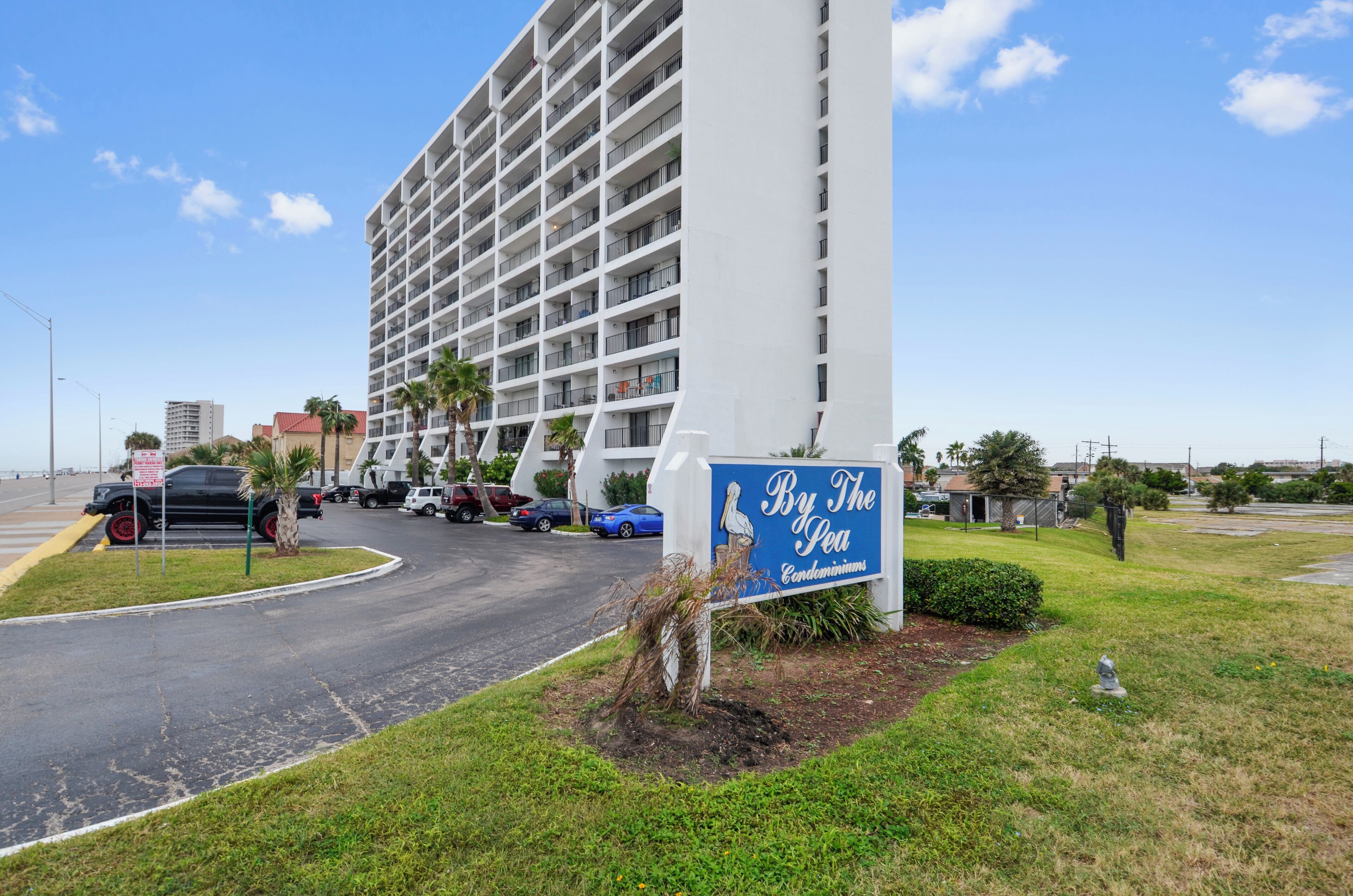 Een groot gebouw met een bord waarop staat: By The Sea Condominiums.