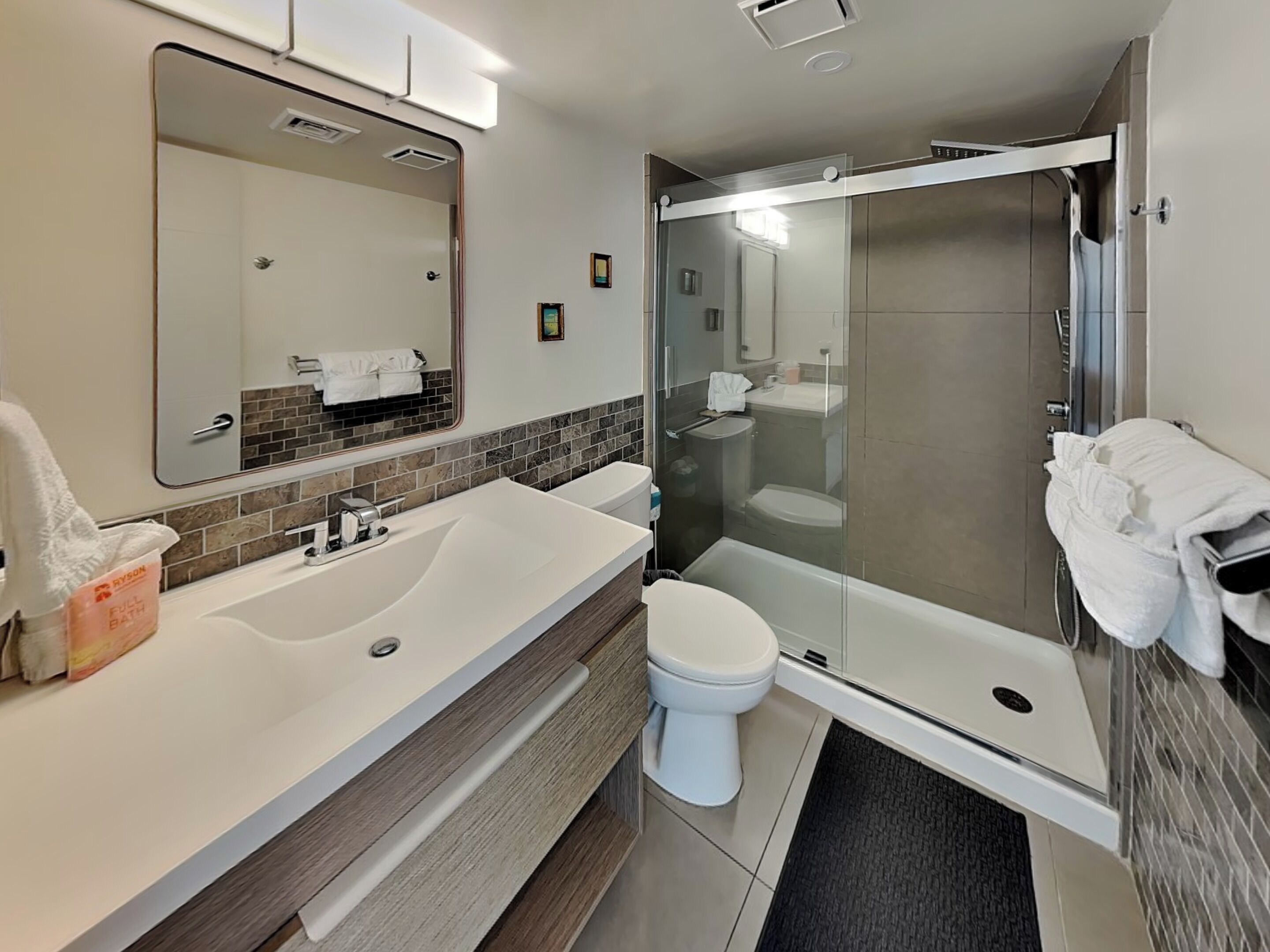 A modern bathroom with a large sink, a toilet, and a glass-enclosed shower.