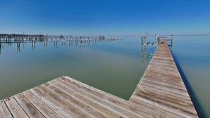 Un muelle de madera que se adentra en aguas tranquilas bajo un cielo despejado.