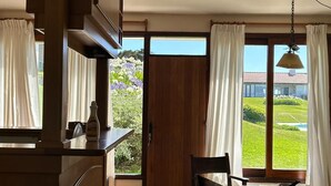 Une cuisine avec un coin repas, de grandes fenêtres et une vue sur un jardin.