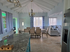 A spacious kitchen with a granite countertop, dining area with chairs, a sofa, and a refrigerator. - Lovely 3 bed home with bedroom AC in St. James, overlooking the Caribbean Sea (Saint James Parish)