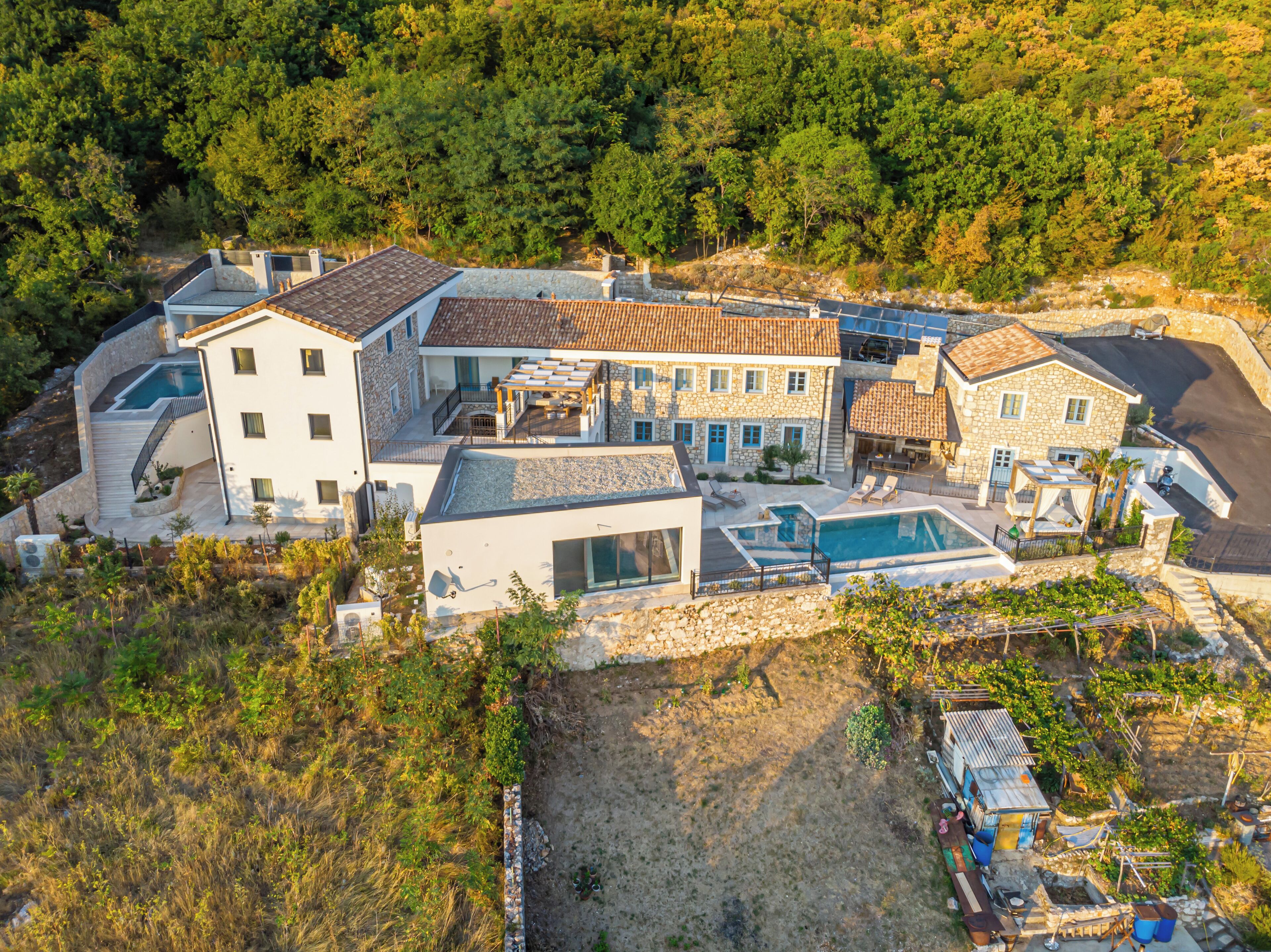 Ein großes, modernes Haus mit Swimmingpool, Steinmauern und Garten.