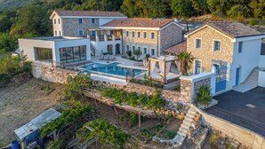 A modern villa with a pool, stone walls, and a mountainous backdrop. - Vinodol Hilltop Estate (Bribir)