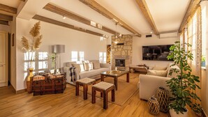 A spacious living room with a wooden floor, a stone fireplace, a sofa, a coffee table, and a large TV. - Vinodol Hilltop Estate (Bribir)