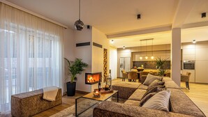 A modern living room with a fireplace, a sofa, a coffee table, and a dining area in the background. - Vinodol Hilltop Estate (Bribir)