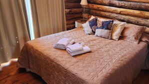 Uma cama com cobertura acolchoada, travesseiros e toalhas dobradas.