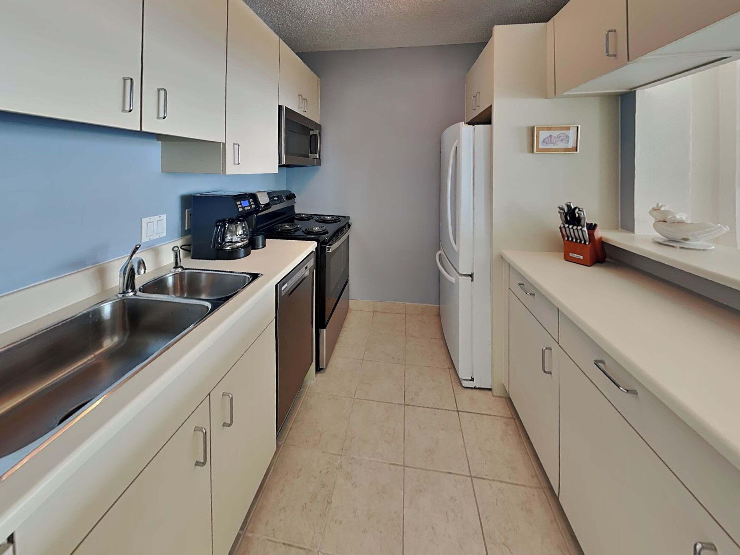 A compact kitchen with a sink, stove, microwave, and refrigerator.