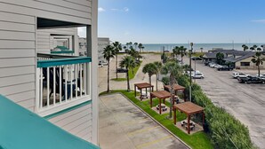 A hotel with a balcony overlooking a parking area, a beach, and a clear sky. - Casa Del Mar 394-stress Free Zone (Galveston)