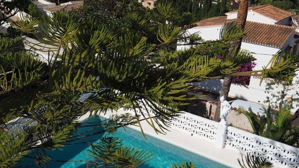 A pool surrounded by lush greenery and white buildings with terracotta roofs. - Villa Palma with magnificent unobstructed view of the mountain (VC)