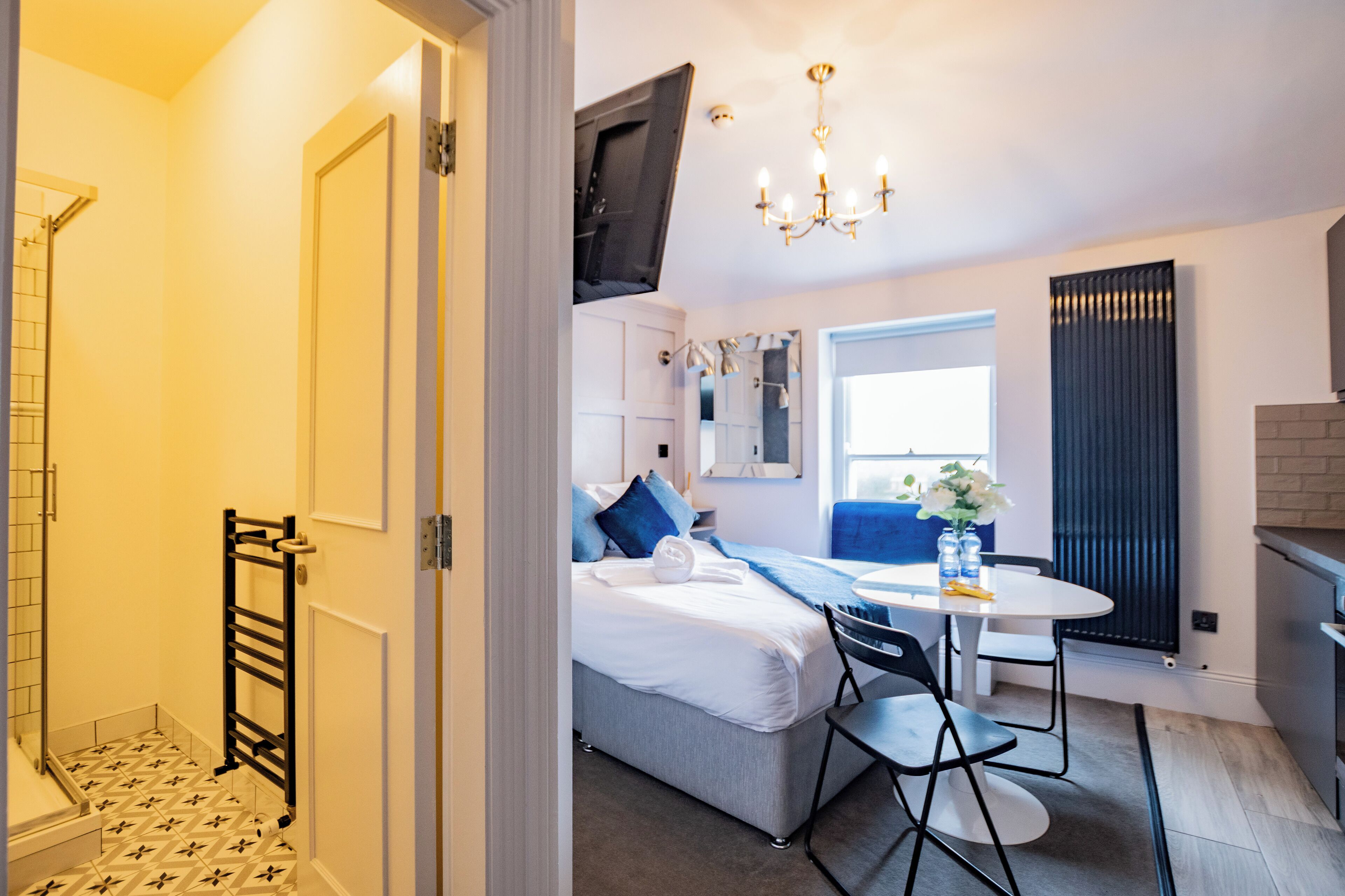 Una habitación de hotel moderna con una cama, una pequeña mesa de comedor y una zona de ducha.