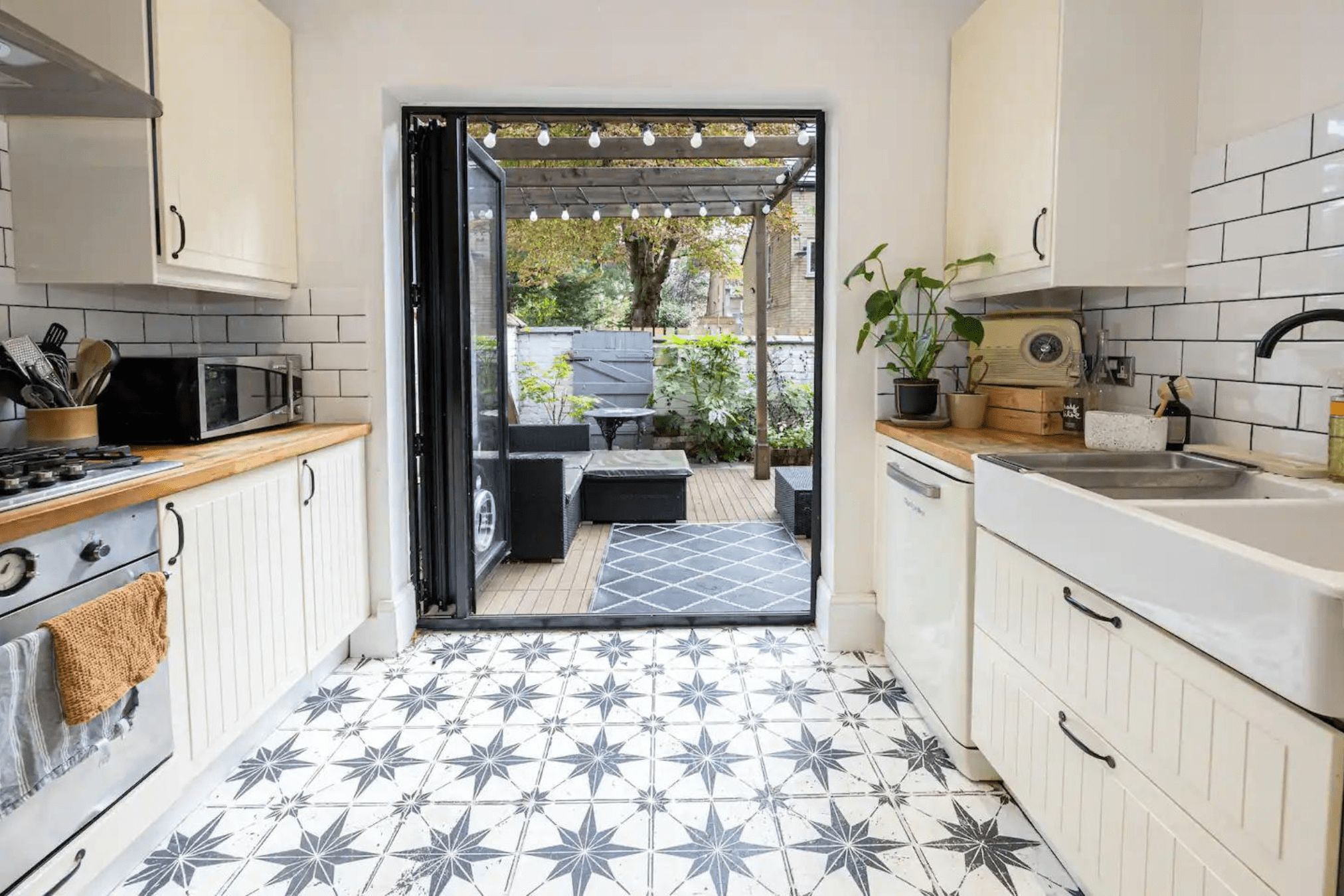 A kitchen with white cabinets, a microwave, a sink, and a dining area with outdoor seating.
