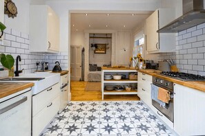 Une cuisine moderne avec des meubles blancs, un carrelage noir et blanc et une cuisinière.