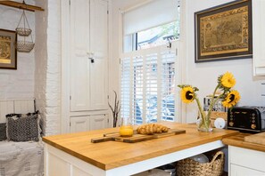 A kitchen with a wooden countertop, a toaster, a vase with sunflowers, and a framed map on the wall. - 1BDR House | Free Parking | Private Outdoor Space (Manchester)