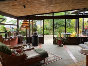 A spacious indoor area with wicker furniture, large windows, and potted plants. - Finca vacation home La Orotava pool + garden + fruit and chickens (La Orotava)