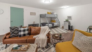 Ein kompakter Wohnraum mit Etagenbett, einer Couch, einem Couchtisch und einem kleinen Beistelltisch.