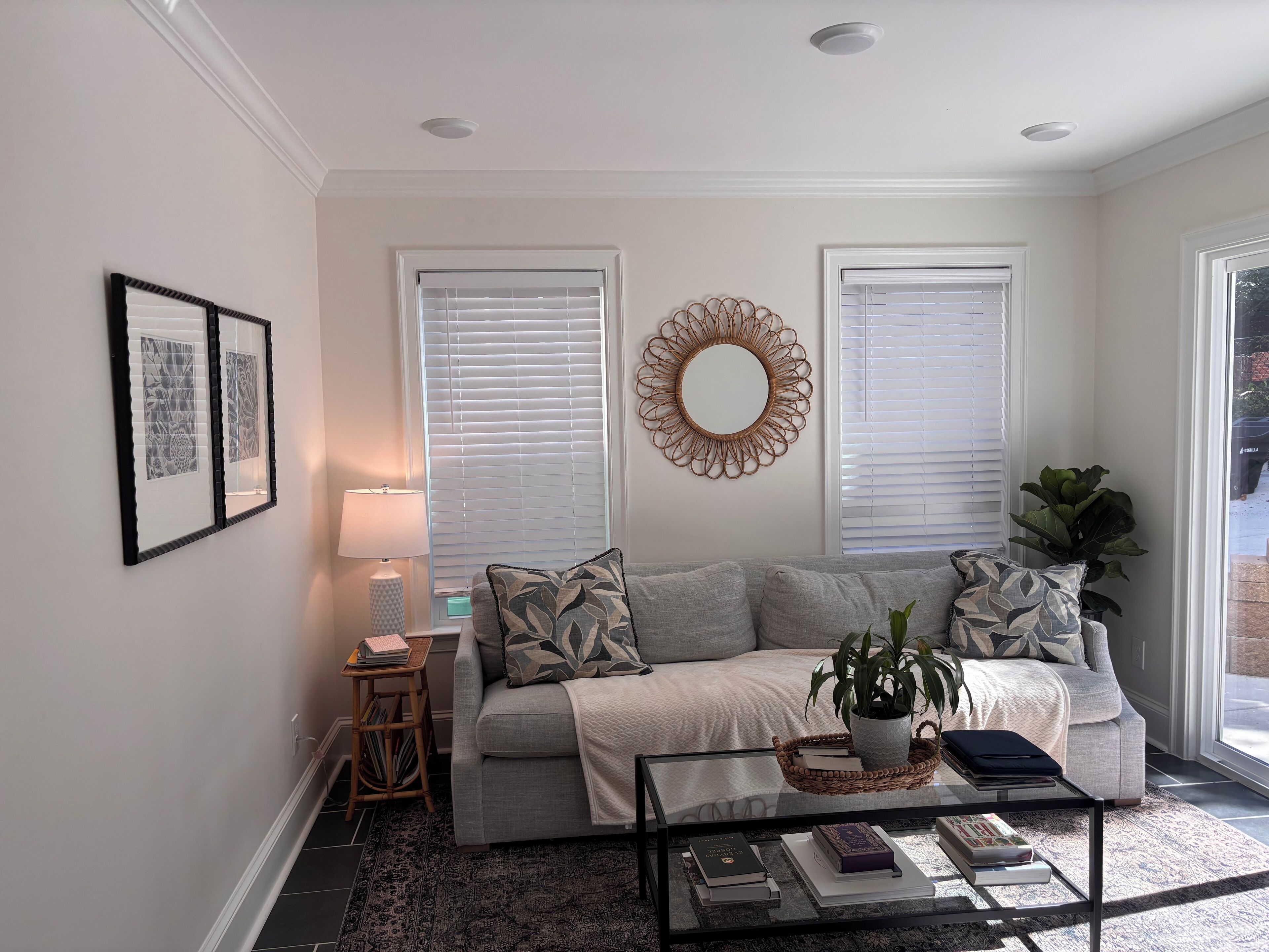 A living room with a sofa, a coffee table, a lamp, and framed artwork on the wall.