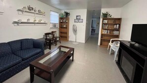 A living room with a sofa, a coffee table, a TV, and a bookshelf. - “The Retreat” with two balconies free parking (Atlantic City)
