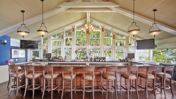 A bar area with wooden bar stools, a large island with a bar counter, and hanging pendant lights. - Escape to Abbey Springs! 2 bedroom, 1 Bath Condo in Private Gated Community (Fontana-on-Geneva Lake)