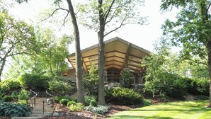 A building with a stone facade, a sloped roof, and a staircase leading to the entrance. - Escape to Abbey Springs! 2 bedroom, 1 Bath Condo in Private Gated Community (Fontana-on-Geneva Lake)