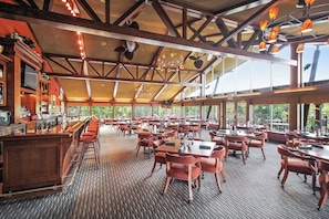 Ein geräumiges Restaurant mit hohen Decken, freiliegenden Holzbalken und großen Fenstern, die einen Blick ins Freie ermöglichen.