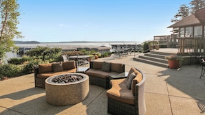 An outdoor patio with wicker furniture, a fire pit, and a view of the water. - Escape to Abbey Springs! 2 bedroom, 1 Bath Condo in Private Gated Community (Fontana-on-Geneva Lake)