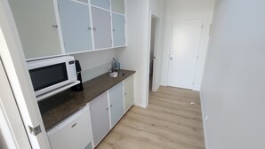 A compact kitchen with a microwave, sink, and cabinets. - Absolute beach front comfort and luxury. (Waihi Beach)