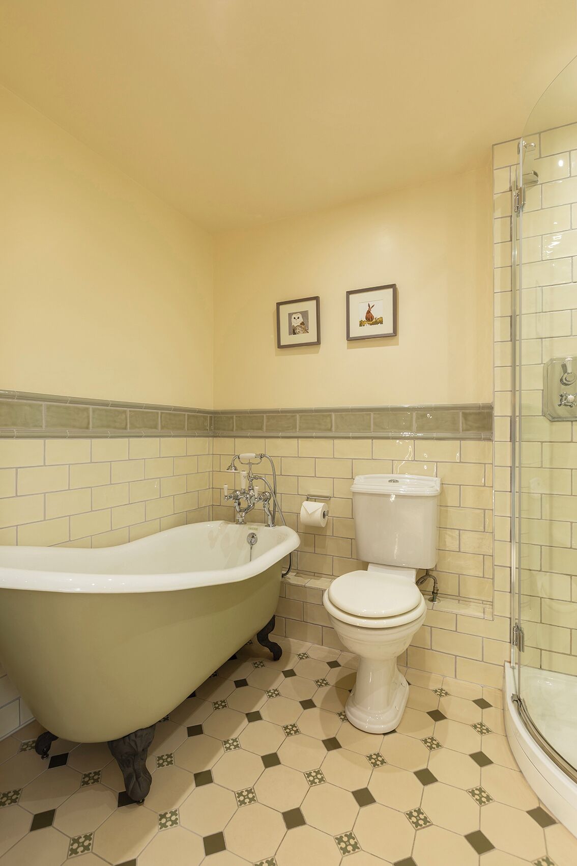 Un baño con una bañera independiente, un inodoro y una ducha con mampara de cristal.