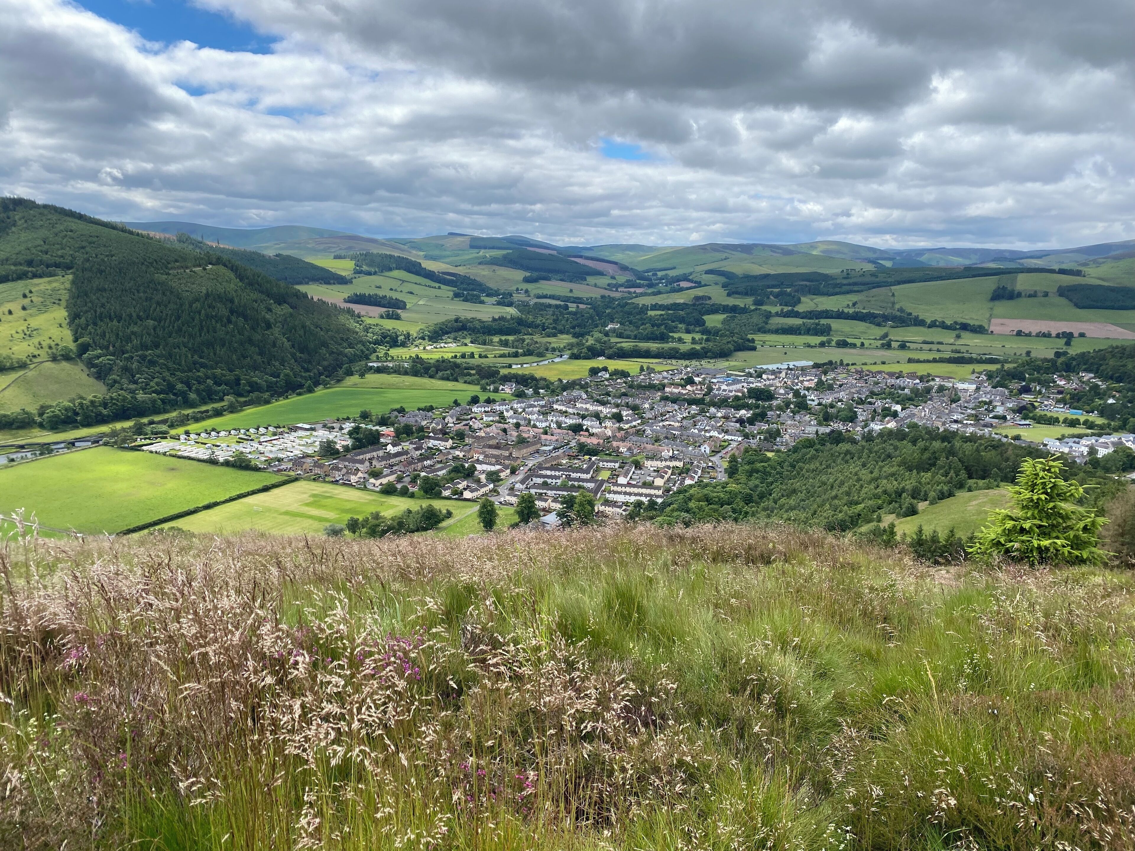 A town nestled in a valley with rolling hills in the background.